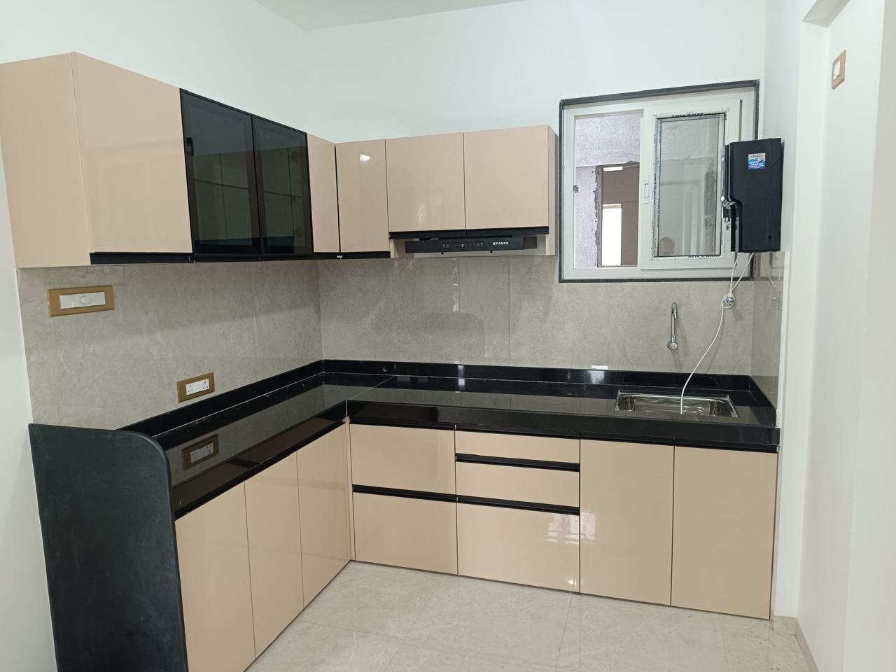 L-shaped modular kitchen in beige gloss with black glass wall cabinets