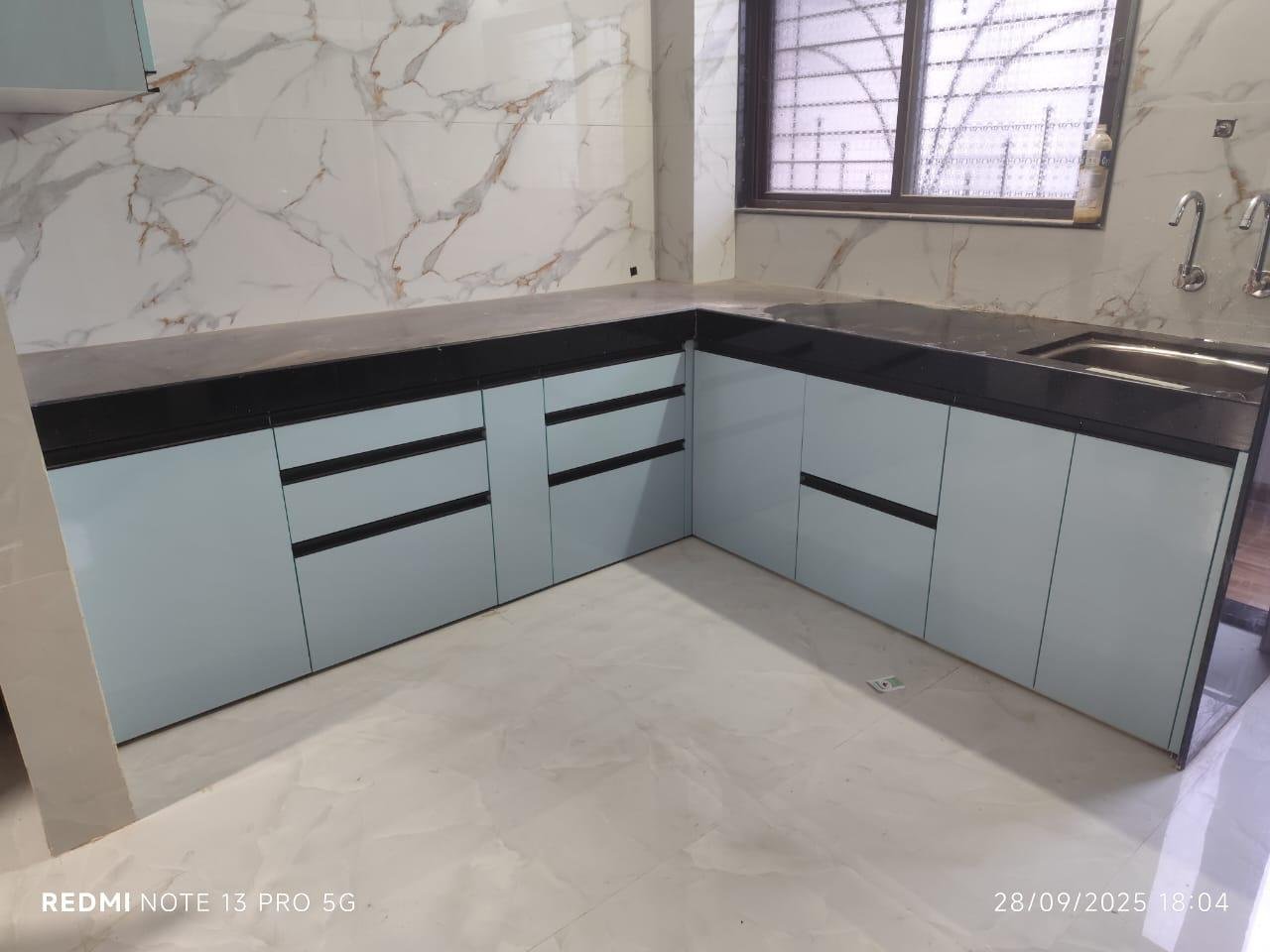 L-shaped modular kitchen in pastel green with a marble-look backsplash