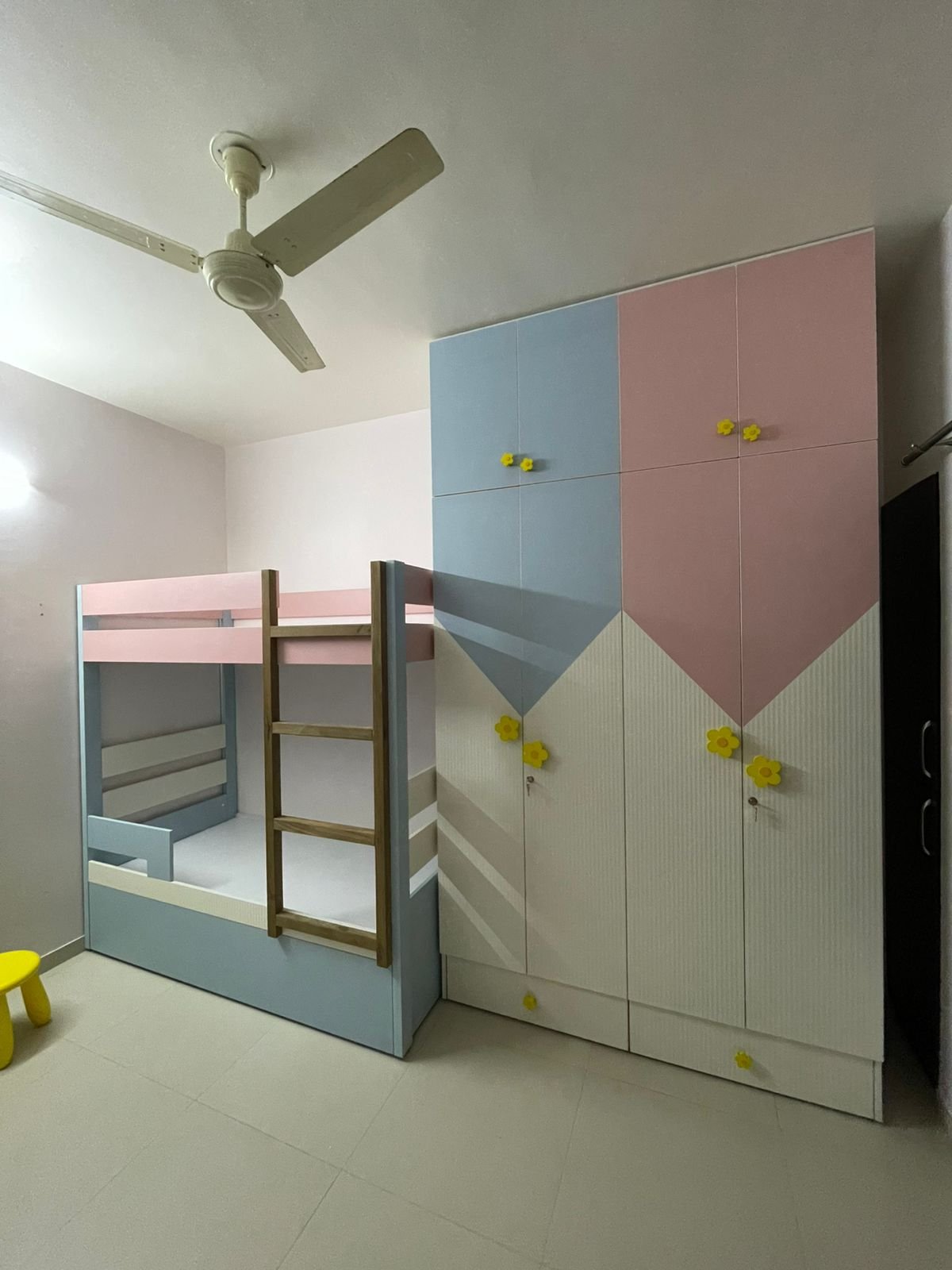 Pastel bunk bed with a colour-blocked wardrobe wall and yellow flower pulls