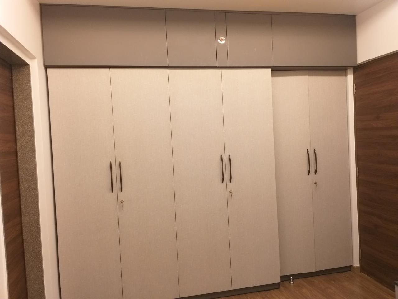 Beige laminate wardrobe wall with loft cabinets and slim handles