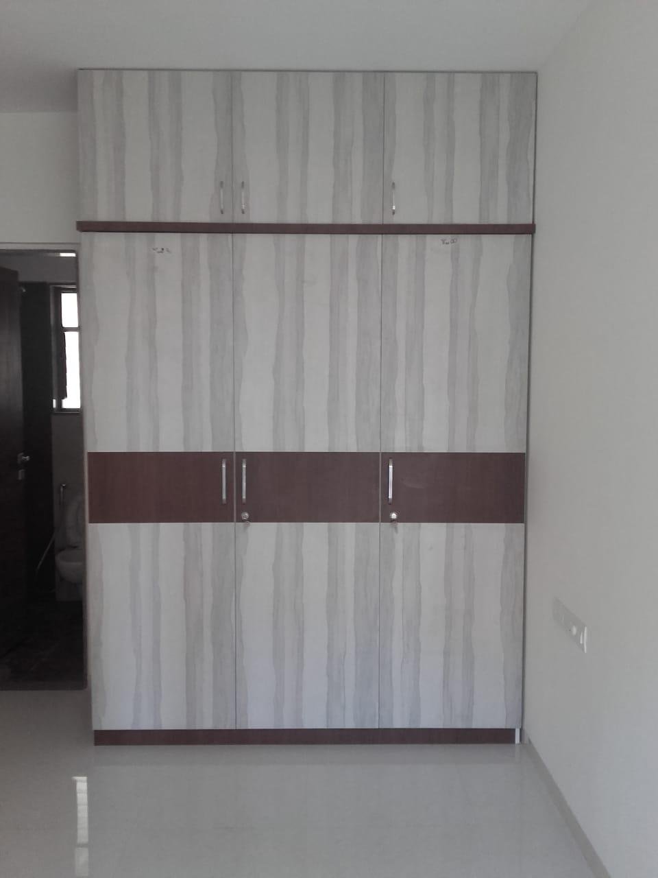 Three-door bedroom wardrobe in matte laminate with matching loft cabinets above