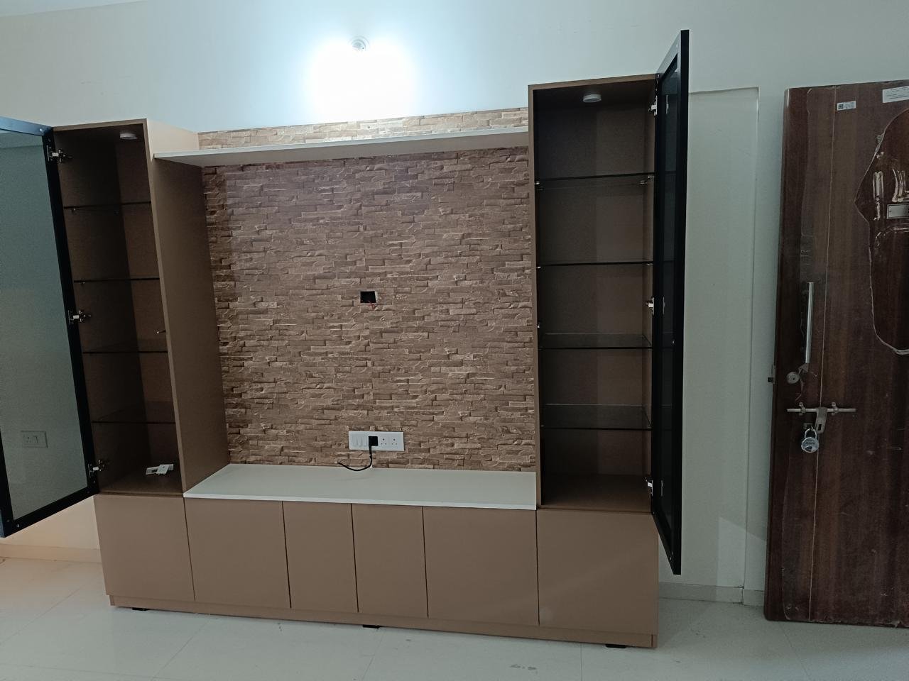 TV unit with a textured stone accent panel flanked by tall glass display cabinets